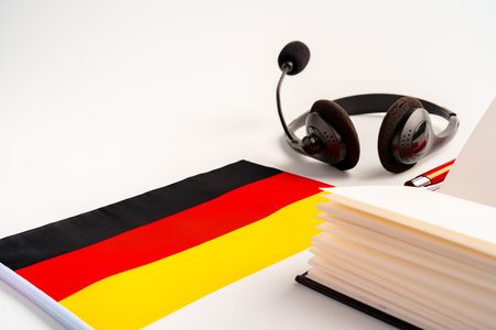 Notepad with German flag and headphones on white background. German language audio courses educational conceptの写真素材