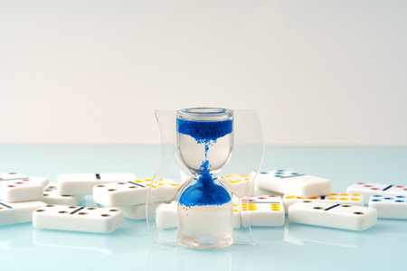 Hourglass and domino tiles on blue background. Time limit conceptの写真素材