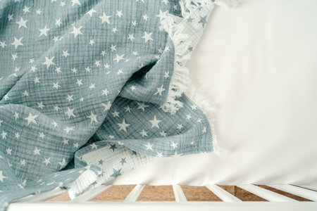 Soft blue muslin blanket hanging on a babys bed