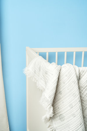 Muslin baby blanket hanging on childs bed in nursing roomの写真素材