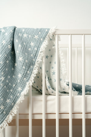 Soft blue muslin blanket hanging on a babys bed