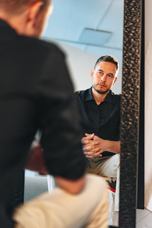 Young man looking at himself in the mirrorの写真素材