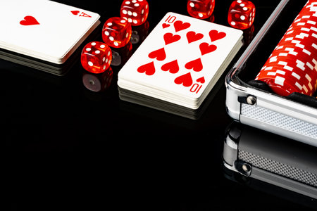 Playing cards and poker chips on black background
