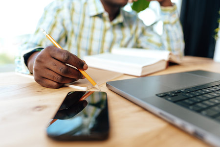 Close up photo of african businessman making notes while sitting at the table in officeの写真素材