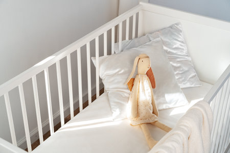 Wooden white baby crib and toy rabbit close upの写真素材