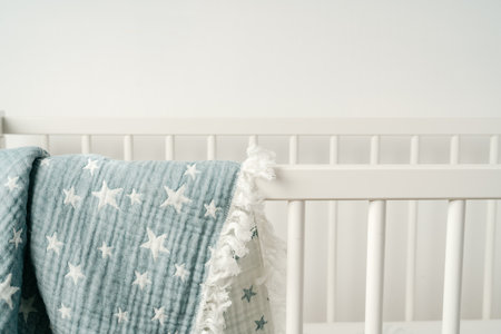 Soft blue muslin blanket hanging on a babys bedの写真素材