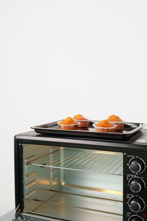 Electric mini oven and baked hot muffins close up