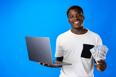 Young african man holding laptop against blue background