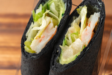 Tortilla wrap with shrimps and vegetables on wooden backgroundの写真素材