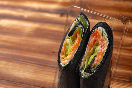 Black tortilla wrap with salted salmon and vegetablesの写真素材