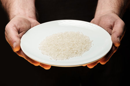 Hands holding a heap of dry rice grain on black backgroundの写真素材