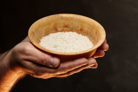 Hands holding a heap of dry rice grain on black backgroundの写真素材