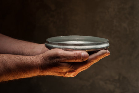 Male hands holding empty plate on dark background, lack of food, hunger concept.の写真素材