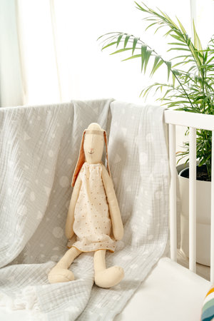 Wooden white baby crib and toy rabbit close up