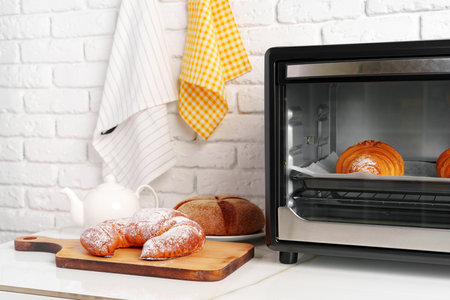 Modern mini electric oven with freshly baked croissants in kitchenの写真素材