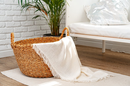 Wicker basket with cozy blanket in a roomの写真素材