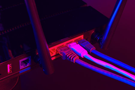 Cables plugged in a Wi-Fi router on dark backgroundの写真素材