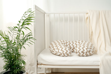 White wooden baby crib with pillow in nursery roomの写真素材