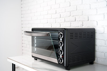 Mini electric oven against white brick wall in the kitchenの写真素材