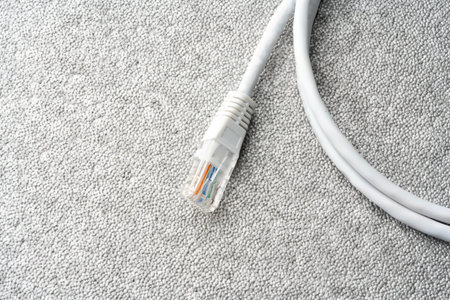 White network cable patch-cord on gray textured background