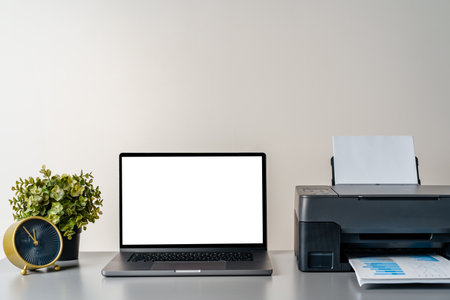 Printer and laptop on grey table in office
