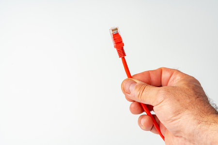 Mans hand holding internet cable on white backgroundの写真素材
