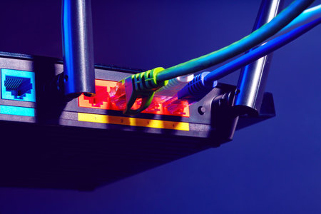 Cables plugged in a Wi-Fi router on dark backgroundの写真素材