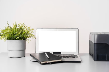 Printer and laptop on grey table in office