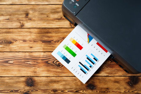 Modern laser printer with paper on wooden backgroundの写真素材