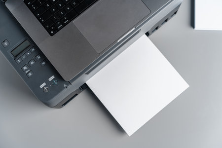 Printer and laptop on grey table in office