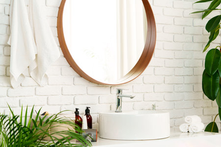 Bathroom interior with circle shaped mirror in wooden frame and white sinkの写真素材