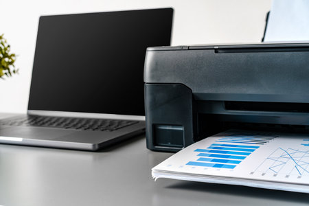 Printer and laptop on grey table in officeの写真素材