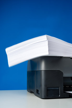 Laser printer on desk against blue background.