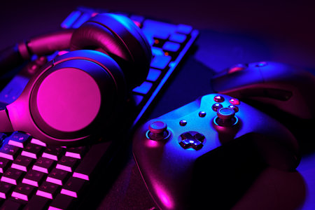 Headphones, joystick and computer keyboard on black table