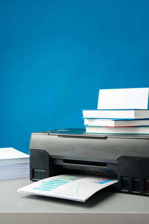 Laser printer on desk against blue background.の写真素材