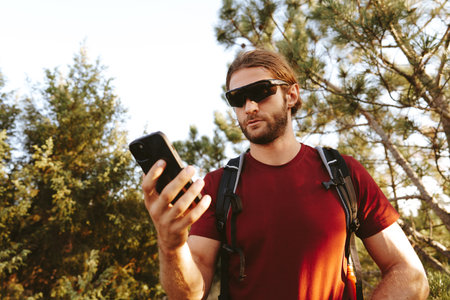Hiker man with backpack checks the route on his phone on the walking trailの写真素材