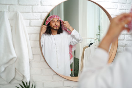 Young Arab man getting ready and looking at the mirror in the bathroomの写真素材