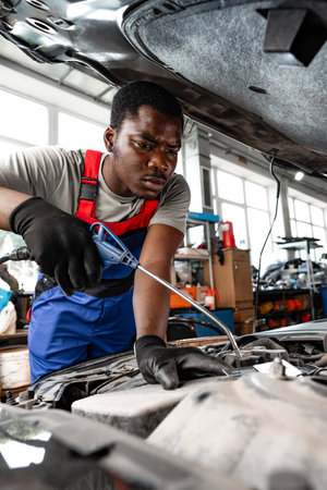 Young African male mechanic repairs car in garage close upの写真素材