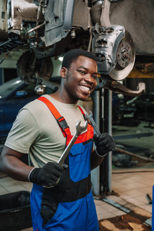 Portrait of young african man car service worker wearing uniform standing in garageの写真素材