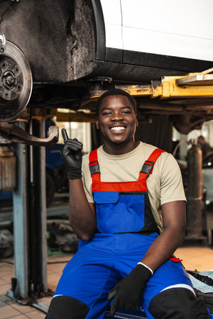 Portrait of young african man car service worker wearing uniform standing in garageの写真素材