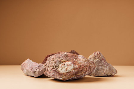 Piece of granite stone against beige background with shadows