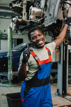 Portrait of young african man car service worker wearing uniform standing in garageの写真素材