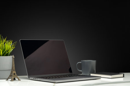 Laptop with green leafy potted plant on black backgroundの写真素材