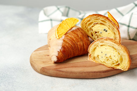 Glazed croissant with dried orange on wooden board
