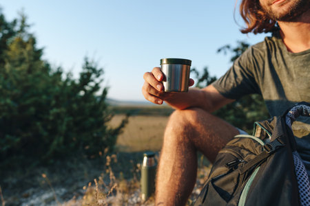 Hiker man with backpack holding cup in his handの写真素材