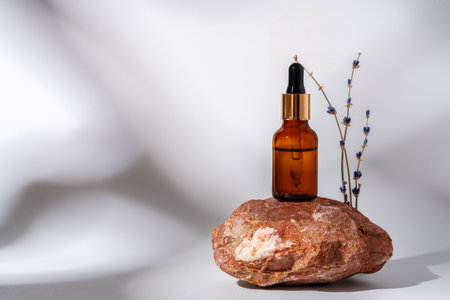 Cosmetic serum in an amber glass bottle with dropper lid with granite stone for compositionの写真素材