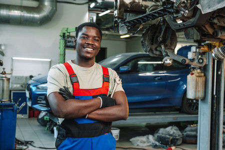 Portrait of young african man car service worker wearing uniform standing in garageの写真素材