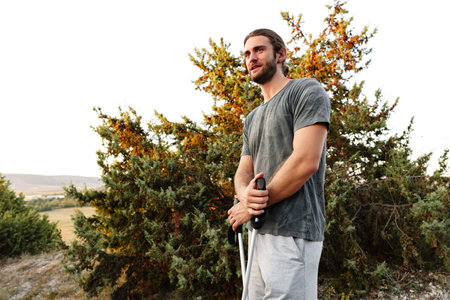 Young man hiker travels through the mountains with trekking poles for nordic walking
