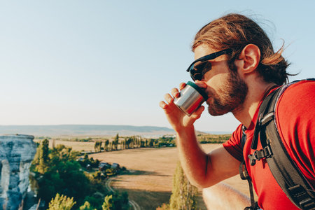 Hiker man with backpack holding cup in his handの写真素材