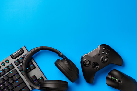 Computer keyboard and joystick on blue background top view